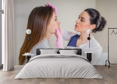 Professional cosmetician examining face skin of girl in clinic of esthetic cosmetology Wall mural