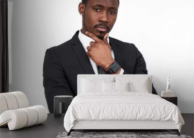 serious African american businessman touching chin wearing black suit isolated on white background  Wall mural