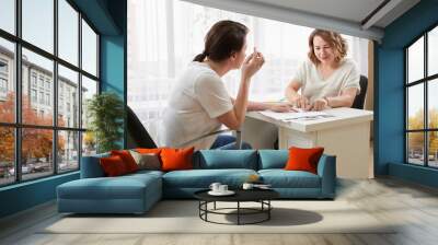 Young woman studying with private tutor at a table taking notes and reading Wall mural