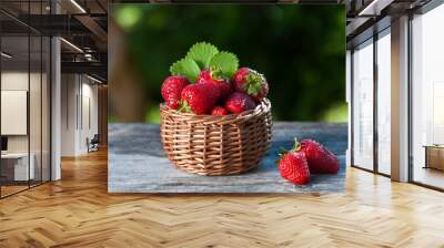 Juicy strawberries in a wicker basket, wooden table, against the backdrop of a beautiful background green garden. Cooking, food industry, restaurant business, gardening, proper nutrition Wall mural