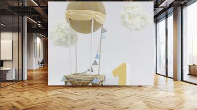 A decorative holiday balloon with a basket, tags and clouds installed in a photo studio and a big number one Wall mural