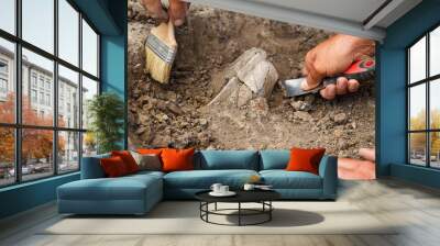 Archaeological excavations, archaeologists work, dig up an ancient clay artifact with special tools Wall mural