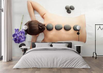 Stone treatment. Top view of beautiful young woman lying on front with spa stones on her back.  Beauty treatment concept. Wall mural