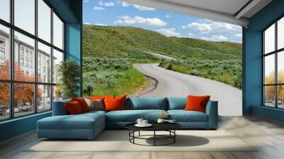 A winding road ascending the hill side toward a blue sky. Wall mural