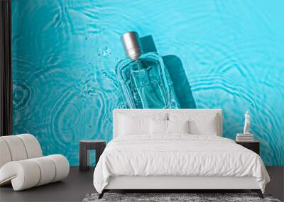 Transparent glass cosmetic perfume bottle in the blue water . Top view Wall mural