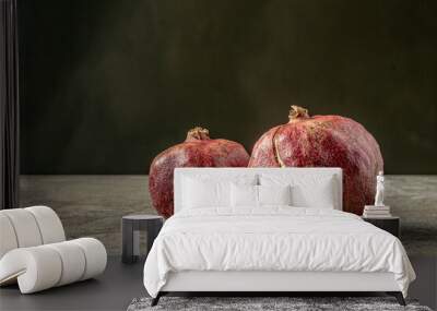 Two ripe pomegranates placed side by side on a dark background. Close-up view showcasing the vibrant red seeds and textured skin of the fruits. Ideal for nutritionists, dietitians, and as a key ingred Wall mural