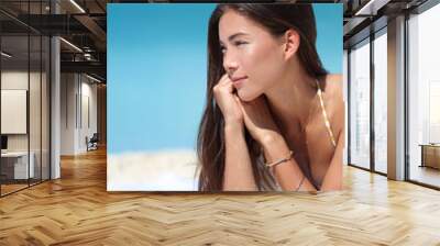 Asian beauty woman relaxing on beach during summer vacation travel. Face closeup of Chinese Caucasian mixed race fashion model posing with bracelets and sun care makeup for skincare concept. Wall mural