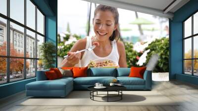 Asian woman eating a fresh raw tuna dish, hawaiian local food poke bowl, at outdoor restaurant table during summer travel vacation. Hawaii poke bowl food plate. Ahi tuna hawaiian cuisine. Wall mural