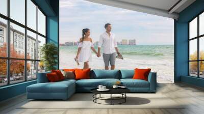 Beach couple romantic sunset walk Asian woman and Caucasian man relaxing walking on Florida vacation beach travel holidays wearing white dress and linen clothes. Happy interracial relationship. Wall mural