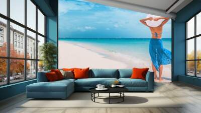 Beach vacation happy woman walking on summer travel Caribbean holiday with arms behind head wearing sun hat and sarong skirt. Ocean panoramic banner background. Elegant lady tourist. Wall mural