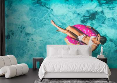 Beach vacation woman relaxing in pool float donut inflatable ring floating on turquoise ocean water background in Caribbean travel summer banner panorama. Girl in white bikini top drone view. Wall mural