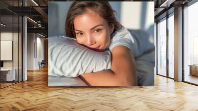 Beautiful Asian woman relaxing at home on pillow bed in bedroom candid smiling portrait. Natural beauty healthy skin model face. Wall mural