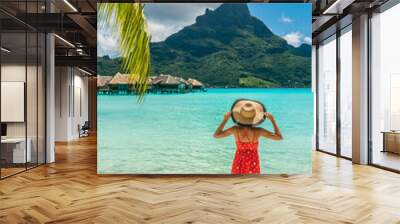 Bora Bora Tahiti exotic tropical vacation destination tourist woman on ocean beach at view of Mt Otemanu in French Polynesia. Girl in red dress and hat relax on honeymoon getaway. Wall mural