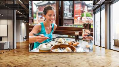 Chinese woman eating at Shanghai restaurant Xiao long bao / xiaolongbao soup dumplings typical food China travel vacation. Asia tourist girl eating Shanghainese steamed dumpling buns with chopsticks. Wall mural