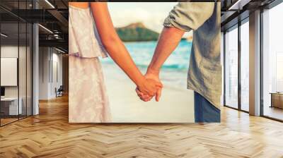 Couple holding hands relaxing on Hawaii beach in sunset. Young people in love in Waikiki travel Honolulu, Hawaii. Wall mural