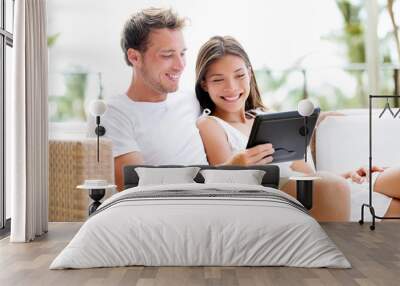 Couple relaxing together in sofa with tablet pc Wall mural