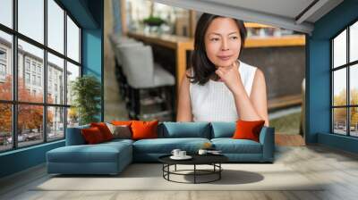 Elegant Asian middle-aged businesswoman pensive portrait. Beautiful mature Chinese business woman relaxing in restaurant bar urban stylish living in Shanghai, China. Mindfulness concept. Wall mural