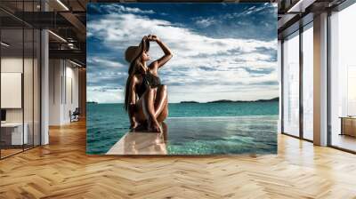 Elegant luxury black swimsuit swimwear model woman with sun hat on infinity pool resort vacation. Europe holiday hotel for wellness spa, hair removal laser legs and body care. Wall mural