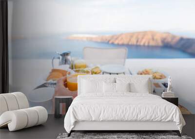 European vacation healthy breakfast food selfie. POV of man drinking morning orange juice at resort restaurant. Table for two on outdoor hotel balcony caldera view on Oia Santorini, Greece, Europe. Wall mural