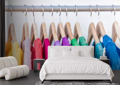 Fashion clothes on clothing rack - bright colorful closet. Closeup of rainbow color choice of trendy female wear on hangers in store closet or spring cleaning concept. Summer home wardrobe. Wall mural