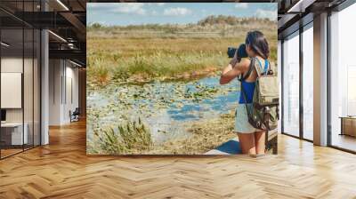 Florida wetlands walking tour woman tourist taking photo with camera of wildlife animal. Bird watching, alligators, fish in the marsh mangrove of the Everglades, Keys, USA. Wall mural