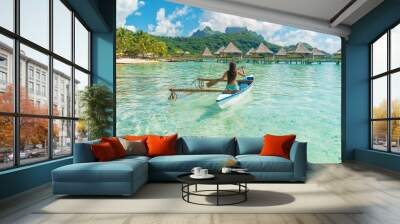 French Polynesia Tahiti travel vacation concept. Outrigger Canoe polynesian watersport sport woman paddling in traditional vaa boat. Water leisure activity, Bora Bora overwater bungalow resort hotel. Wall mural