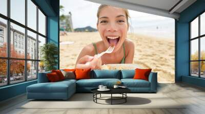 Funny woman eating salad healthy meal on beach Wall mural