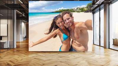 Happy beach couple selfie having fun smiling on Hawaii vacation suntan fit body Asian bikini girl excited with open arms smiling, man taking photo with phone. Wall mural