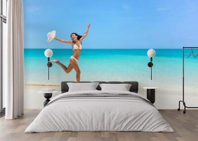 Happy bikini woman jumping of joy and success on perfect white sand beach on caribbean tropical vacation. Holiday girl with sexy slim suntan body running of freedom and happiness. Wall mural