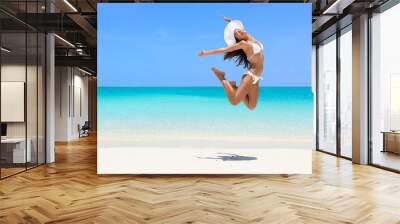 Happy bikini woman jumping of joy on beach. Excited holiday girl doing a jump of freedom and happiness in a free body. Weight loss success healthy lifestyle concept. Wall mural