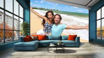 Happy people jumping screaming of fun on beach summer vacation travel in Hawaii. Laughing young Asian woman with Caucasian man, tourists couple friends on holiday. Wall mural