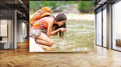 Hiker woman drinking water from river creek hiking Wall mural