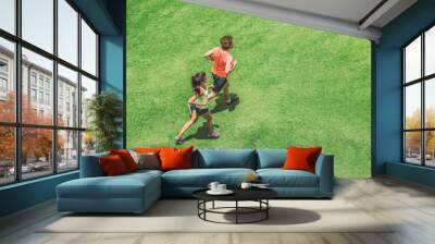 Jogging couple athletes runners running people on grass park top view from above aerial drone. Summer fitness active lifestyle fit people training hiit workout cardio. Wall mural