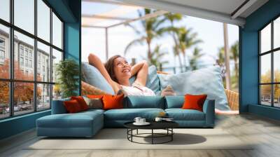 Luxury hotel home living woman relax enjoying sofa furniture of outdoor patio. Beautiful young multiracial Asian girl relaxing day dreaming for rich early retirement in getaway tropical house. Wall mural