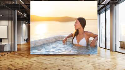 Luxury hotel travel woman in spa pool hotel with Mediterranean sea background. Santorini vacation summer holidays girl enjoying holiday getaway. Asian model relaxing. Wall mural