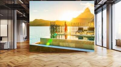 Luxury resort high end hotel rich people lifestyle woman tourist relaxing watching sunset on private balcony terrace of overwater bungalow suite in Bora Bora, Tahiti, French Polynesia. Wall mural