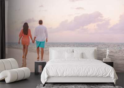 Luxury romantic Caribbean getaway for lovers walking on sunset beach stroll for honeymoon destination. Woman and man couple holding hands going away. Wall mural