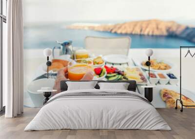 Luxury travel resort breakfast in room service at fancy hotel restaurant with amazing balcony view over Santorini island, Oia, Greece. Europe vacation food selfie. Man drinking morning orange juice. Wall mural