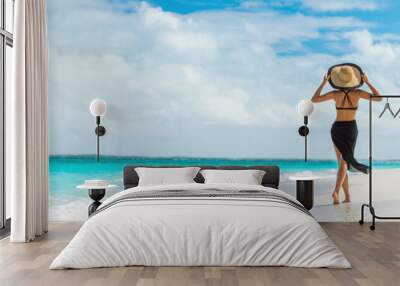 Luxury travel summer beach vacation woman walking in black beachwear skirt and hat on paradise white sand Caribbean beach. Lady tourist on Caribbean holiday vacation resort. Banner panorama landscape. Wall mural