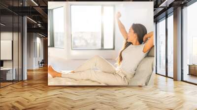 Morning woman waking up stretching in bed in sunshine sunrise early bird happy Asian girl in pajamas on weekend in sun glow. Healthy wake-up routine home lifestyle. Wall mural