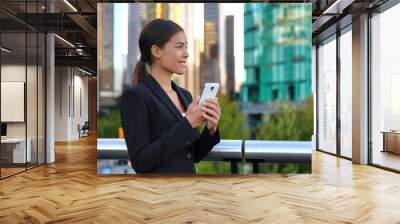 Phone Asian business woman in suit outside texting on mobile smartphone. Happy smiling businesswoman realtor working using smart phone. Young multiracial chinese caucasian lady at work. Wall mural