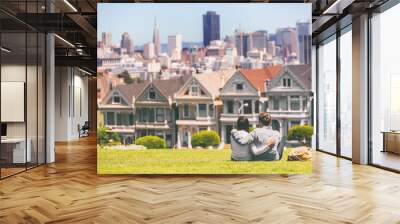 San Francisco - Alamo Square people. Couple tourists relaxing in Alamo Park by the Painted Ladies houses iconic landscape, The Seven Sisters, San Francisco, California, USA. Wall mural