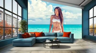 Sexy asian beach model woman beauty showing off toned abs and slim bikini body on tropical caribbean travel vacation. Girl with tanned skin and white fashion swimsuit. Wall mural