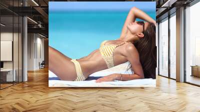 Sexy suntan beach woman sunbathing in fashion bikini. Beautiful fit body of model relaxing tanning on towel. Weight loss or skin care sun protection concept. Wall mural