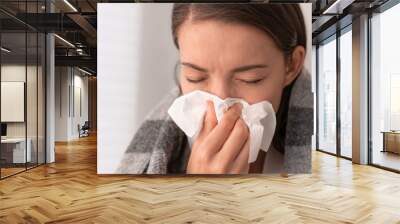 Sick woman feeling unwell staying home. Young girl with flu symptoms coughing in tissue covering nose when sneezing as COVID 19 prevention. Panoramic crop. Wall mural