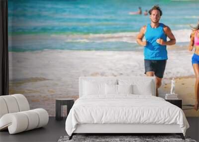 Sport athletes running on beach doing cardio hiit workout exercise. Panoramic banner of couple of two runners training together barefoot on sand with blue ocean. Wall mural