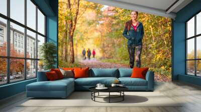 Woman walking in autumn forest nature path walk on trail woods background. Happy girl relaxing on active outdoor activity. Wall mural