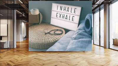 Yoga breathing INHALE EXHALE sign at fitness class on lightbox inspirational message with exercise mat, mala beads, meditation pillow. Accessories for fit home lifestyle. Wall mural