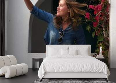 Young woman smiling and waving from window on Greek Meditteranean Island Wall mural