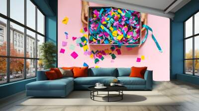 Gift box with colored confetti in children's hands. The view from the top on a pink surface, horizontal frame Wall mural